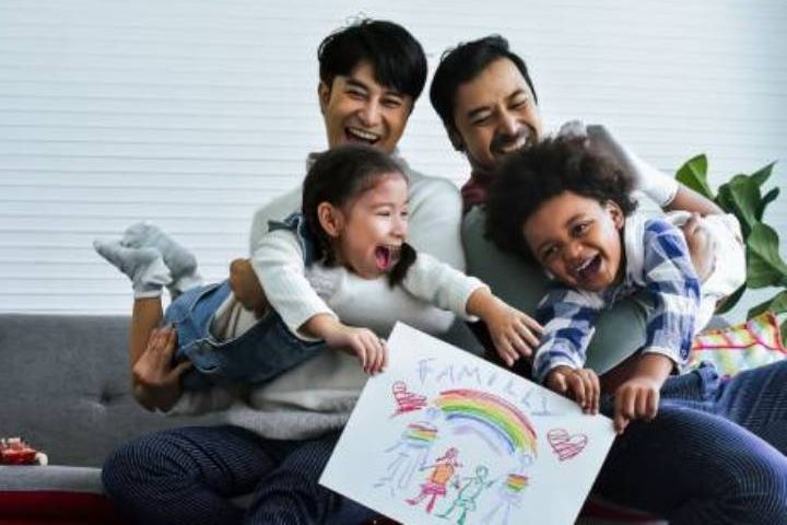 Male couple with smiling foster daughter and son.