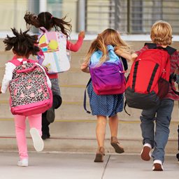 Children running to school wearing backpacks