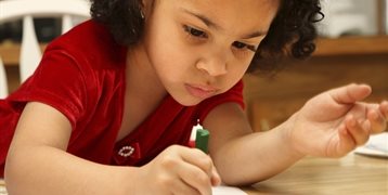 A young girl colouring with a crayon.