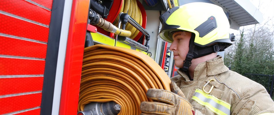 Firefighter reeling in a hose