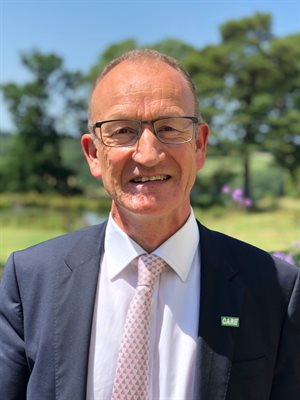 Councillor Richard Roberts wearing a suit outdoors looking at the camera and smiling
