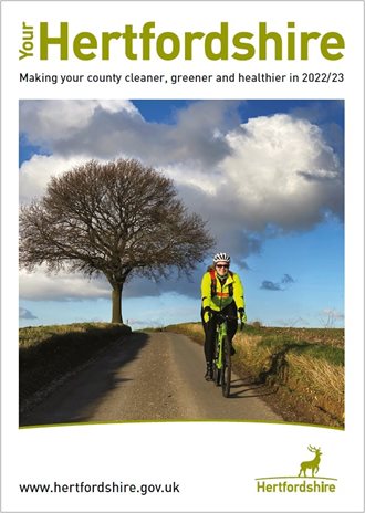 The front cover of Your Hertfordshire magazine - shows a woman riding a bike down a hill.