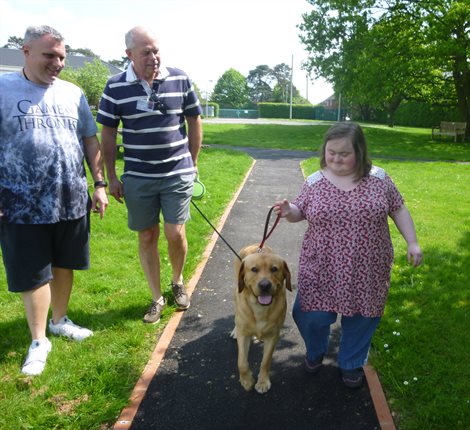 Woman and men walking a dog in a park.