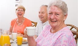 Older women and a man smiling with drinks