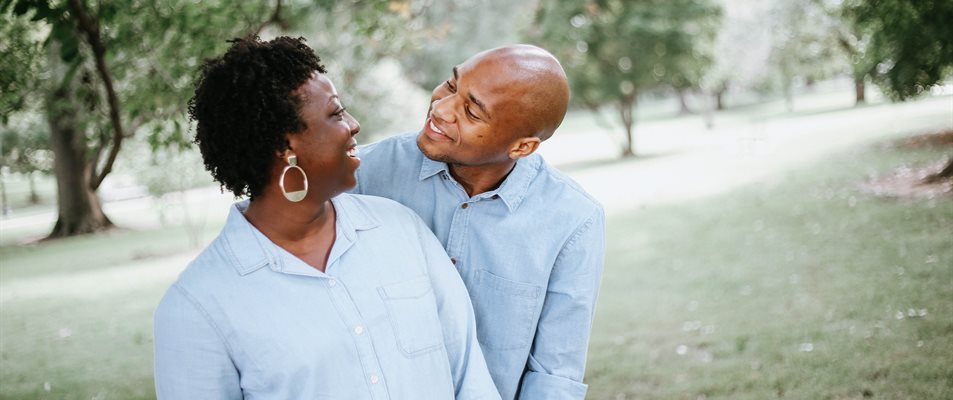 A couple smiling at each other in a park