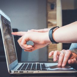 A person pointing at a laptop screen