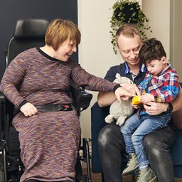 Woman in wheelchair and man with little boy on lap