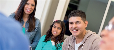 A teenage boy, a young girl and a woman smiling at a meeting.