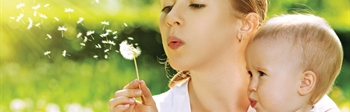 A woman and baby blowing dandelion seeds