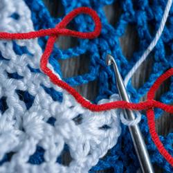 red white and blue yarn and crochet needle