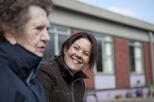 Female helping older female outside a care home