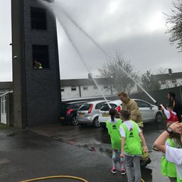 Children and firefighters using hoses