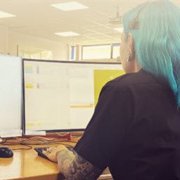 A woman wearing a phone headset looking at 2 computer screens