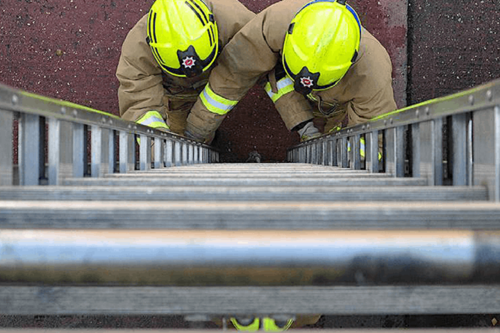 Two firefighters at the bottom of a ladder