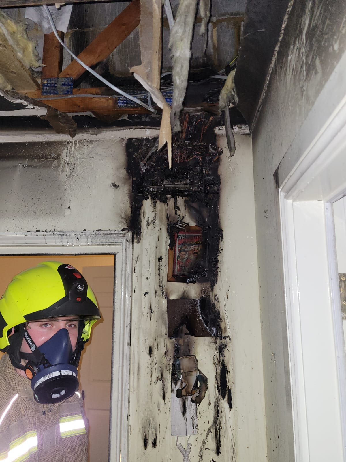 firefighter standing next to a burnt wall