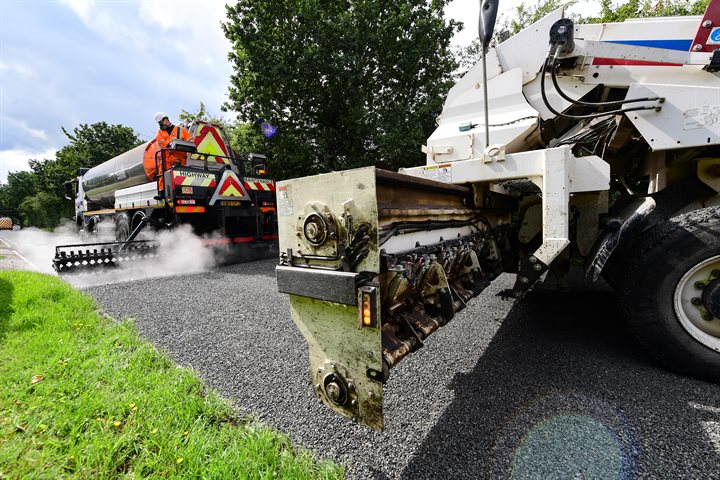 A large machine spreading tarmac on a road