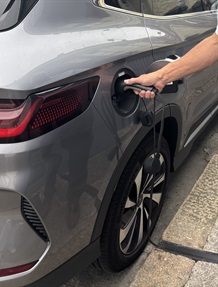 A car being charged via a cross-pavement charging channel
