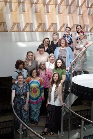 Group of people, creatives and library staff, standing on a curved staircase in the bright interior space of Welwyn Garden City Library.