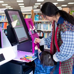 Mum and daughter using a library kiosk