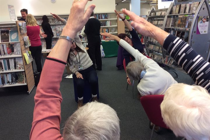 Older people stretching in a library