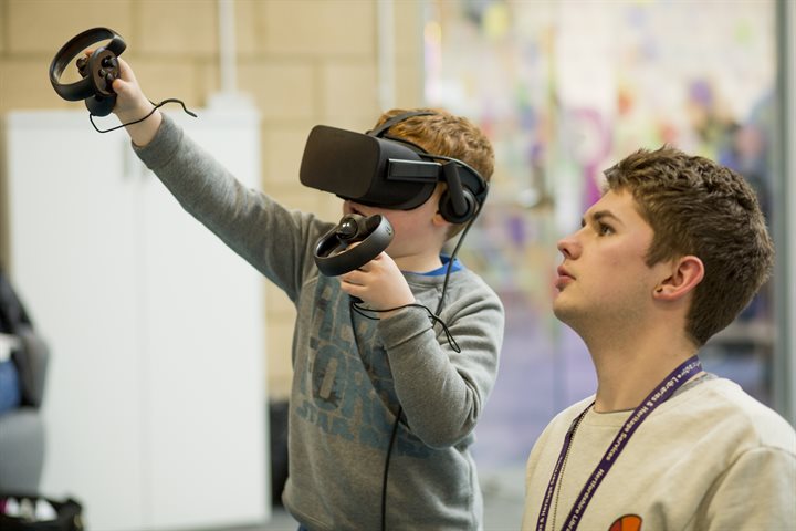 Volunteer helping a boy with a VR headset
