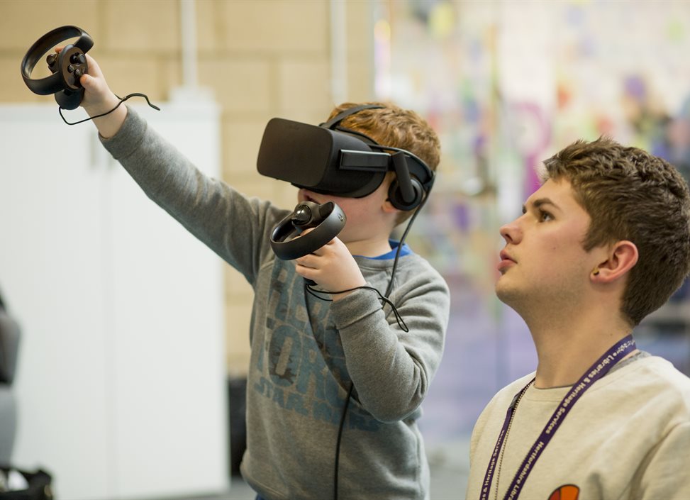 Volunteer helping a boy with a VR headset