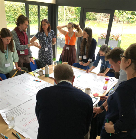 A group discussing ideas around a table with nature recovery strategy worksheets.