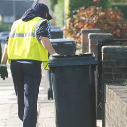 Man pulling a black bin