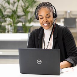 Woman wearing headset and working on a laptop