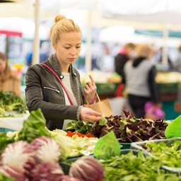 Woman at a market looking at a lettuce