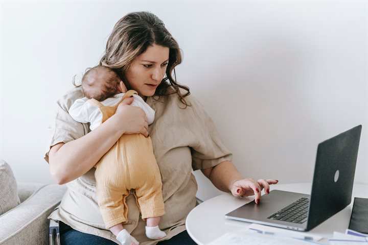 Mum holding baby and looking at laptop