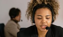 Woman using laptop, wearing a handsfree phone headset