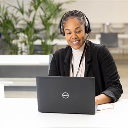 Woman wearing headset and working on a laptop