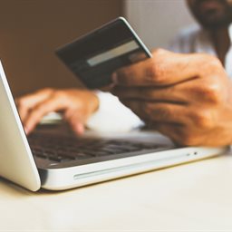 Man holding a credit card and using a laptop