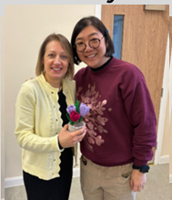 Learner with teacher, holding some flowers.