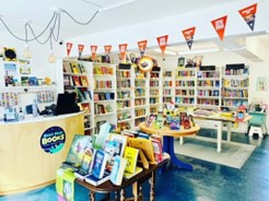 full bookshelves and small tables inside Next Page bookshop